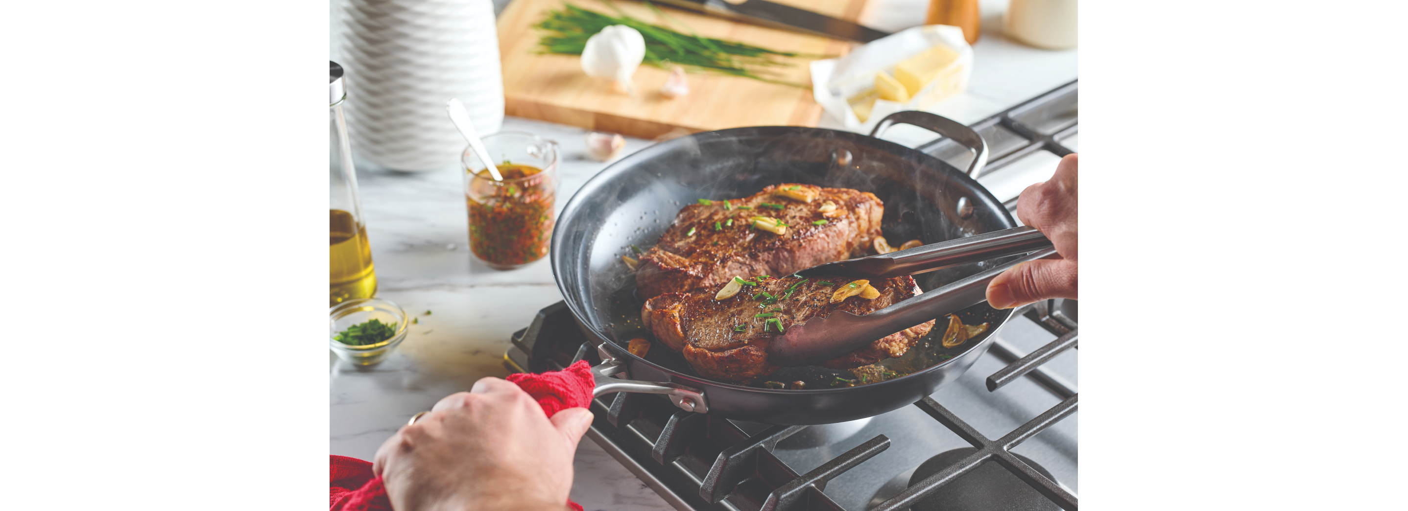 A person cooking steak in a pan.