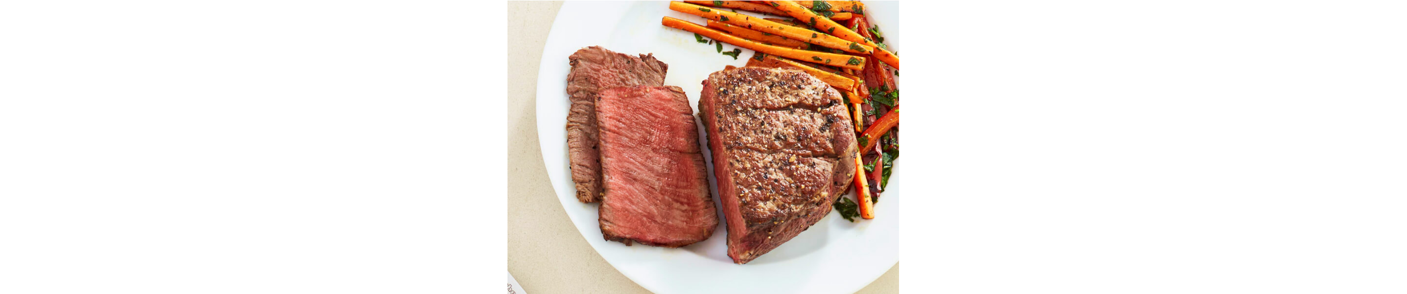 Sliced filet mignon on a plate with julienned carrots