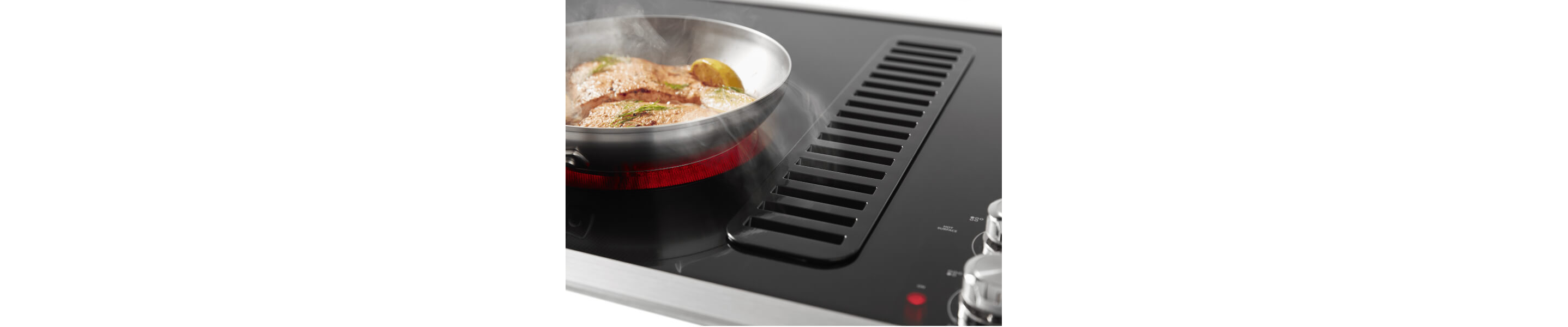 Food cooking on KitchenAid® induction cooktop with downdraft ventilation