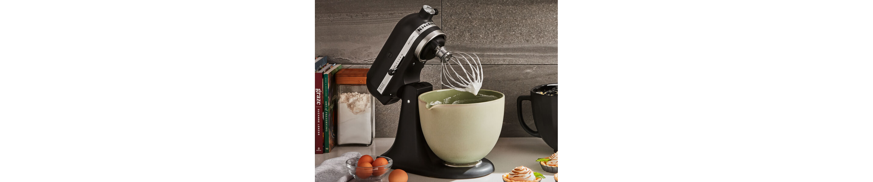KitchenAid® stand mixer with green ceramic bowl and wire whip on countertop