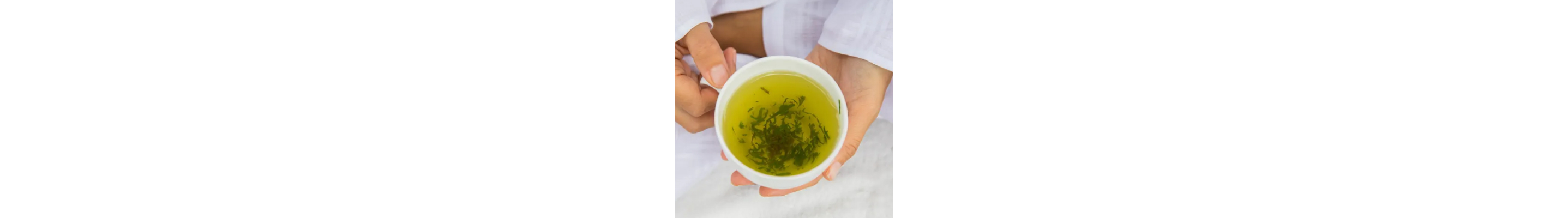 A person holding a white tea cup with ground herbs