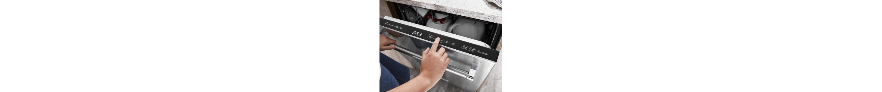 A closeup of a person programming a stainless steel KitchenAid® dishwasher.