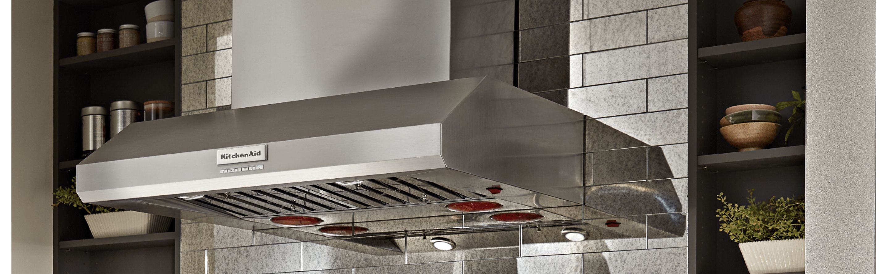 A KitchenAid® range hood against a backdrop of kitchen cabinets