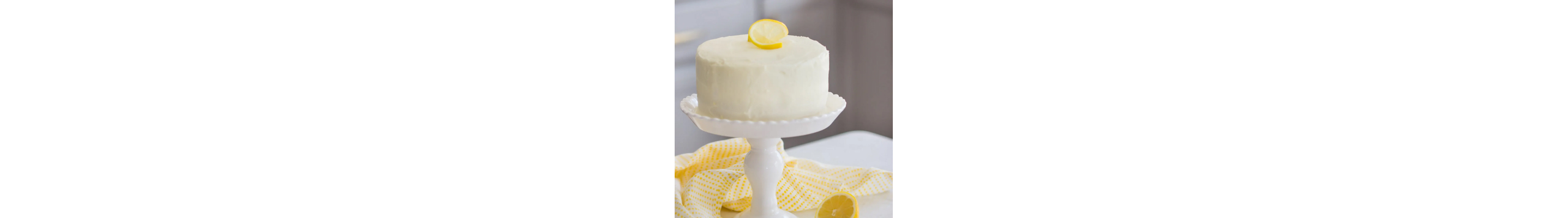 White frosted cake on top of cake stand topped with sliced lemon