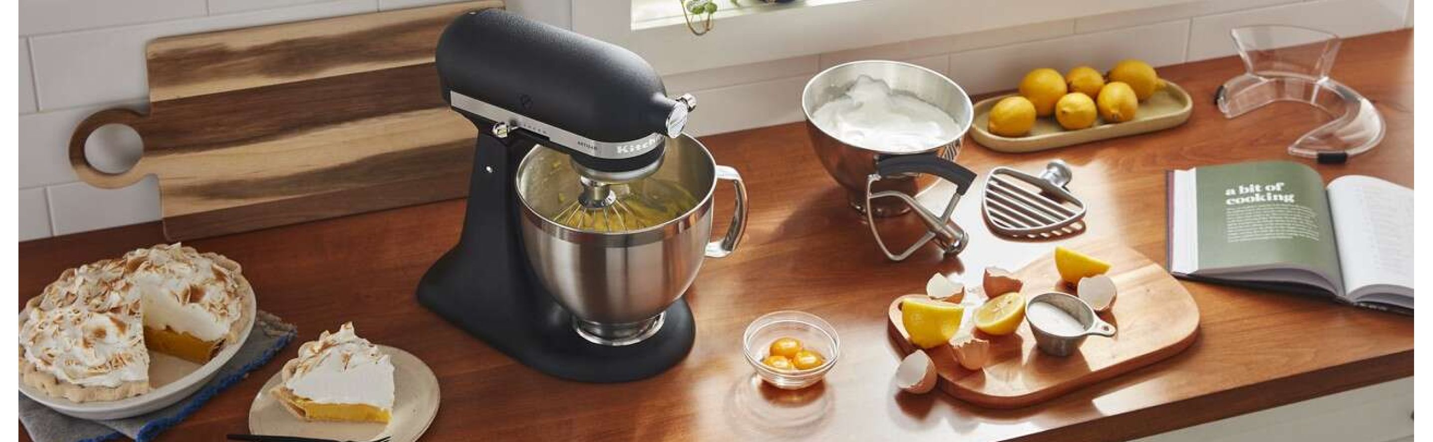 Black KitchenAid® stand mixer on countertop with various ingredients and slice of pie