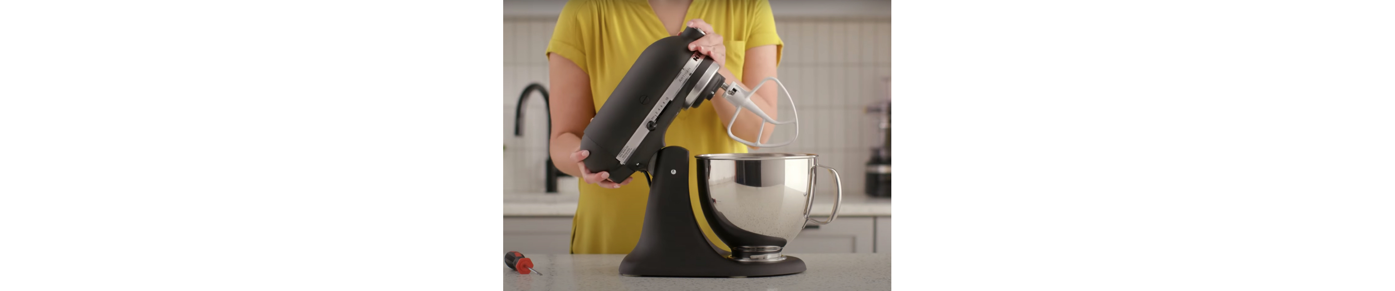 A person tilting back a black tilt-head stand mixer