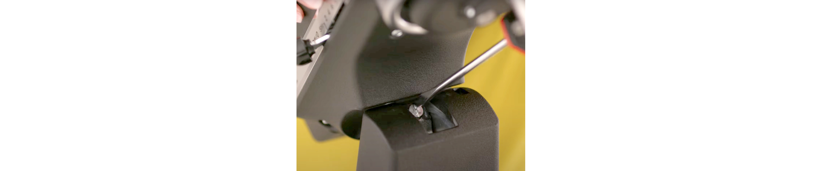 A person adjusting a black tilt-head stand mixer with a flathead