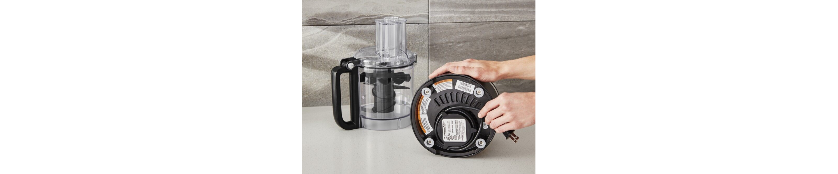 A person holding the power cord of a disassembled food processor