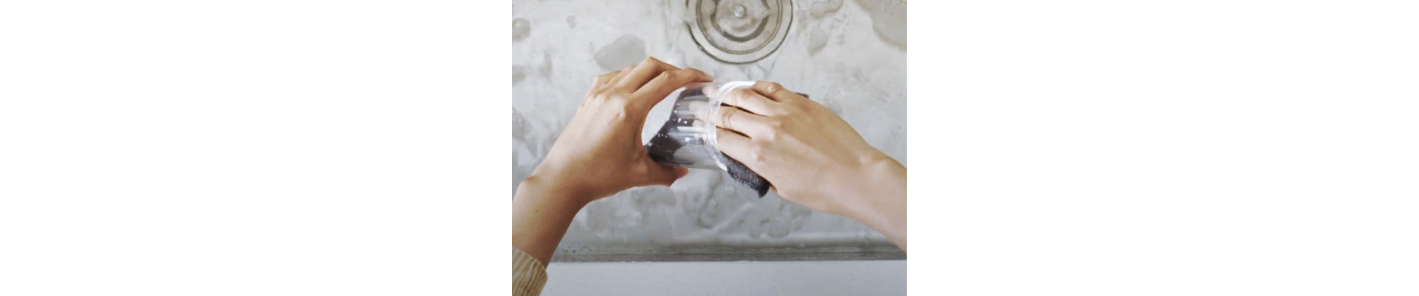 Person washing container with a sponge