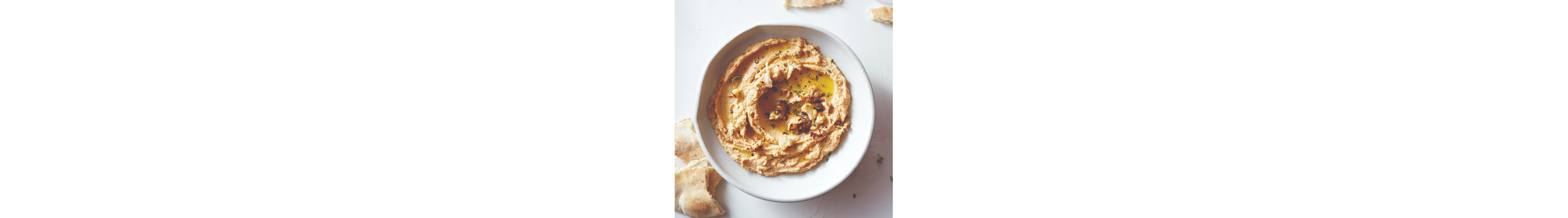 Bowl of hummus topped with herbs and olive oil