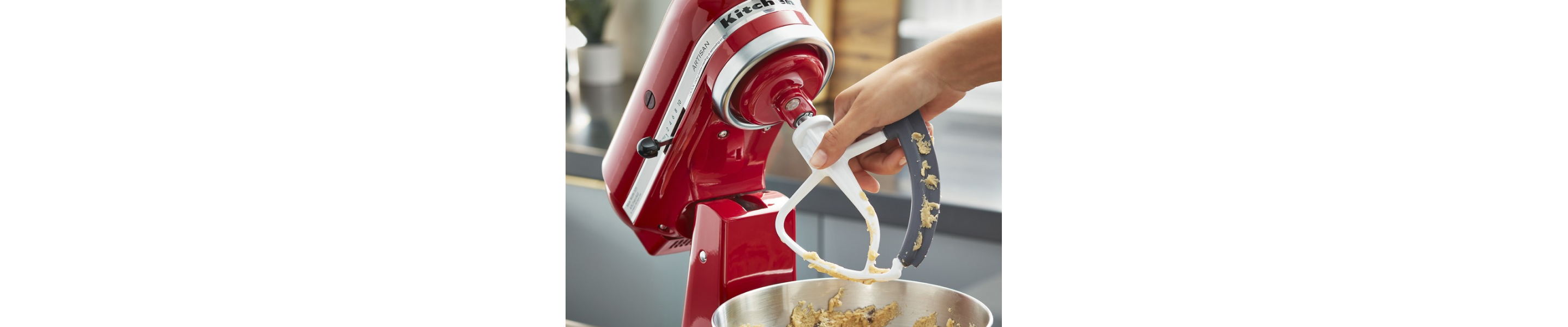 Person removing a KitchenAid® flex edge beater accessory from a red stand mixer