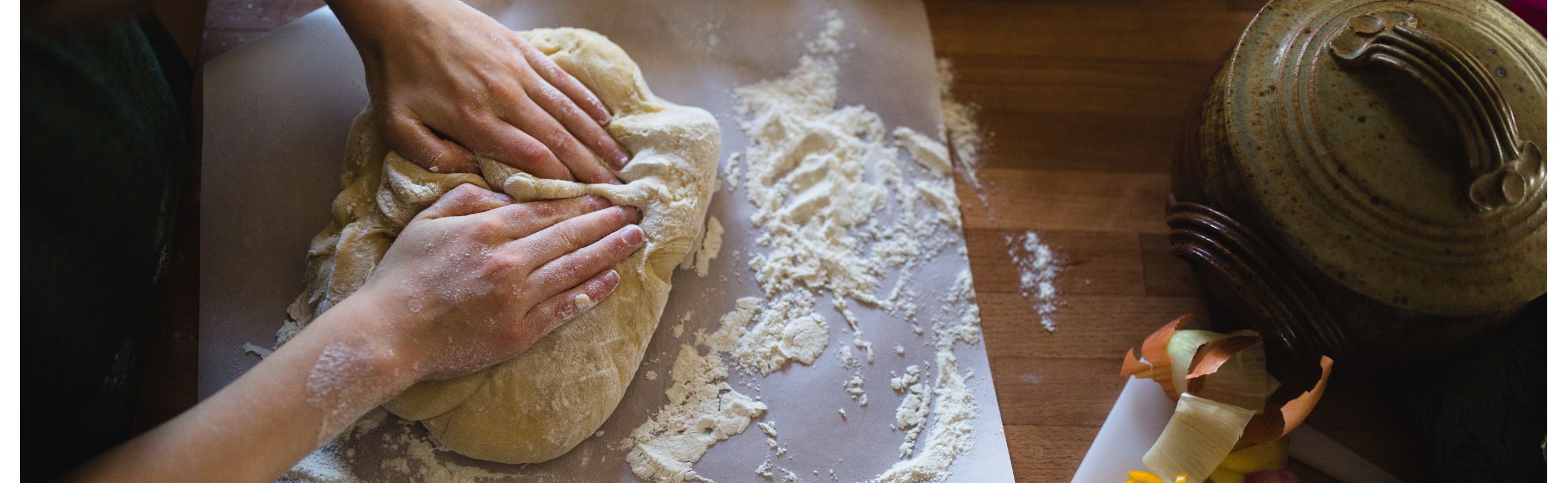 Top view of two hands kneading dough on countertop