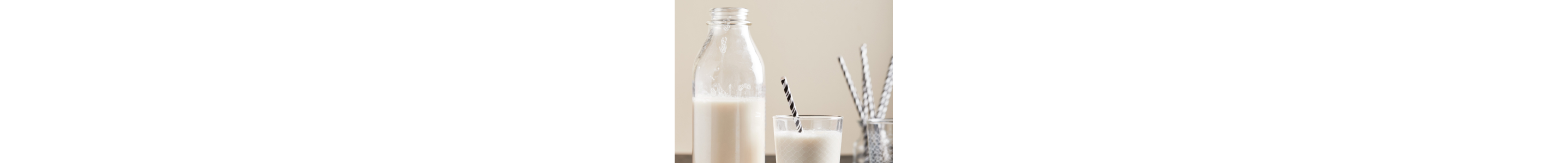 Glass bottle of milk next to glass of milk with gray and white striped straw