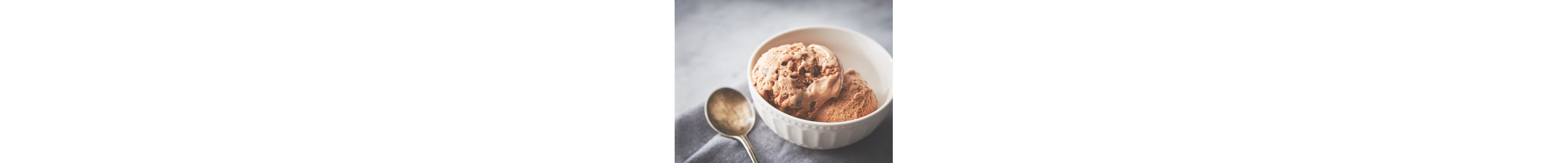 White bowl of chocolate ice cream next to spoon