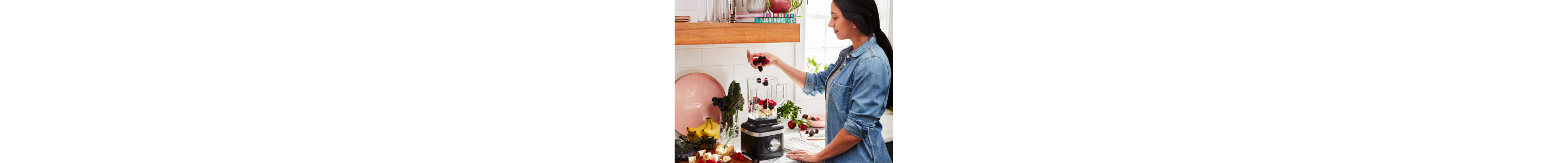 Person filling black blender with ice cream and fruit
