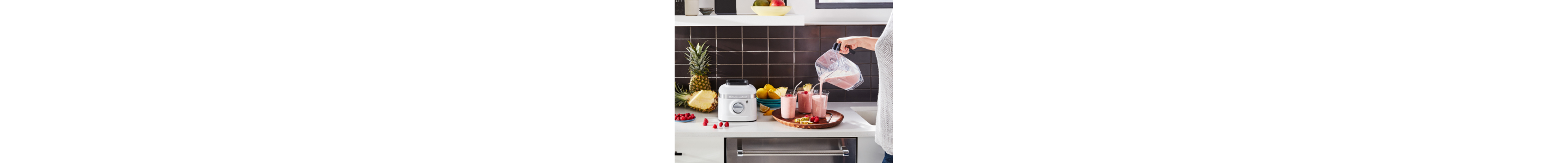 Person pouring strawberry milkshake from blender into glasses 