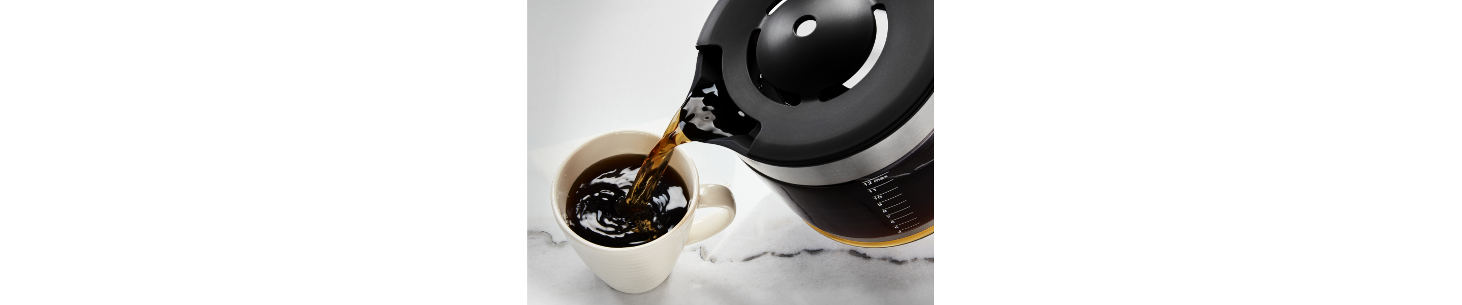 Coffee being poured into a ceramic mug