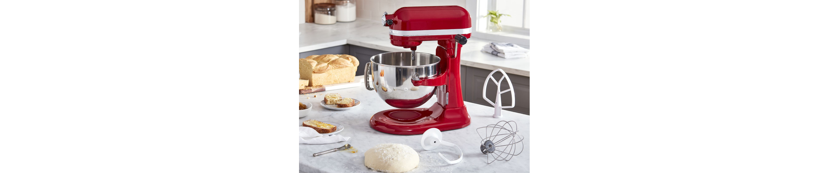 Dough rising on a counter next to a red Kitchenaid® bowl-lift stand mixer and assorted attachments
