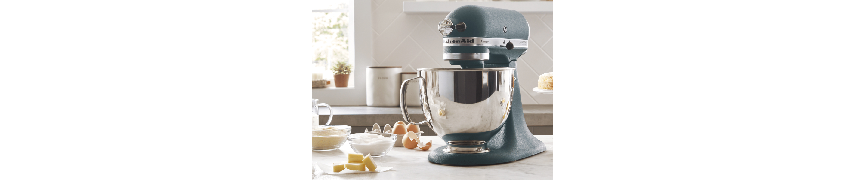 KitchenAid® stand mixer in a modern kitchen next to egg shells, butter, sugar and flour. 