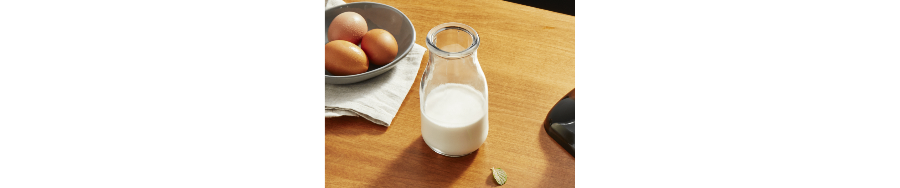  Jar of milk on cutting board next to eggs in a bowl