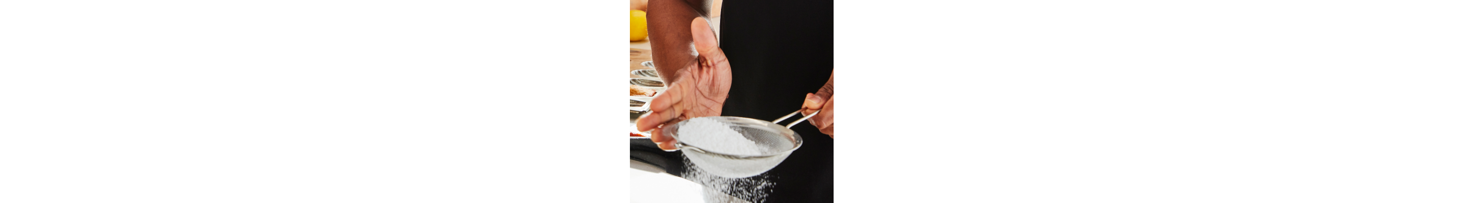 Person sifting powdered sugar with a handheld sifter
