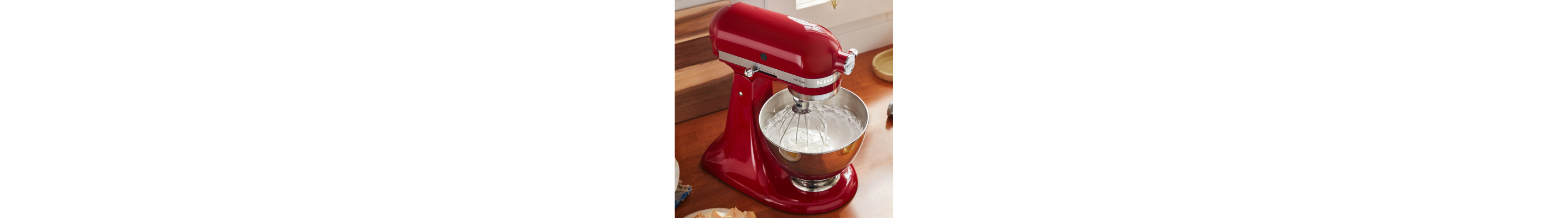 Red KitchenAid® stand mixer with stainless steel bowl and wire whisk attachment
