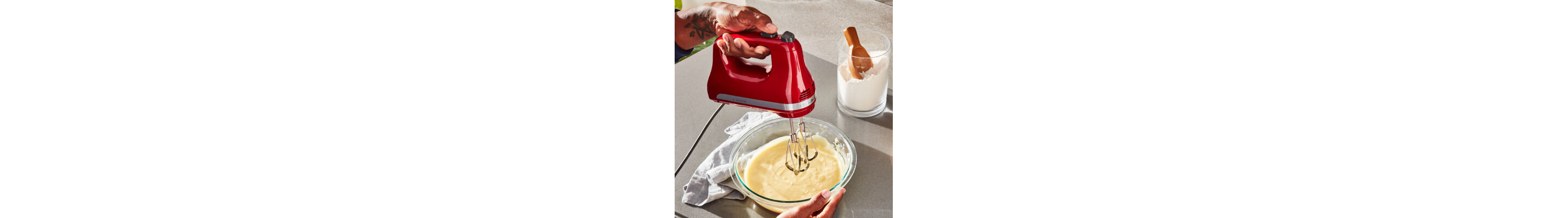 A person using a red KitchenAid® to whip cream