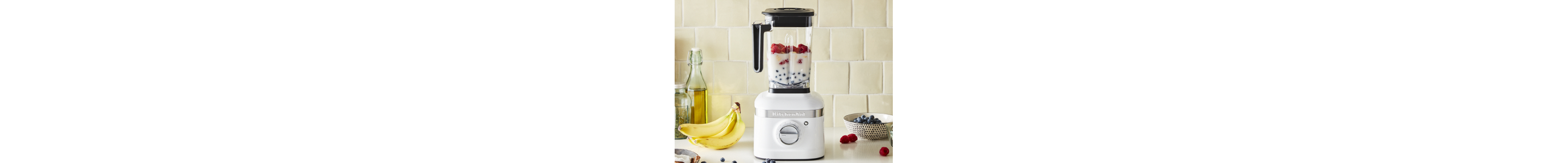 White KitchenAid® blender filled with milk and fruit on countertop