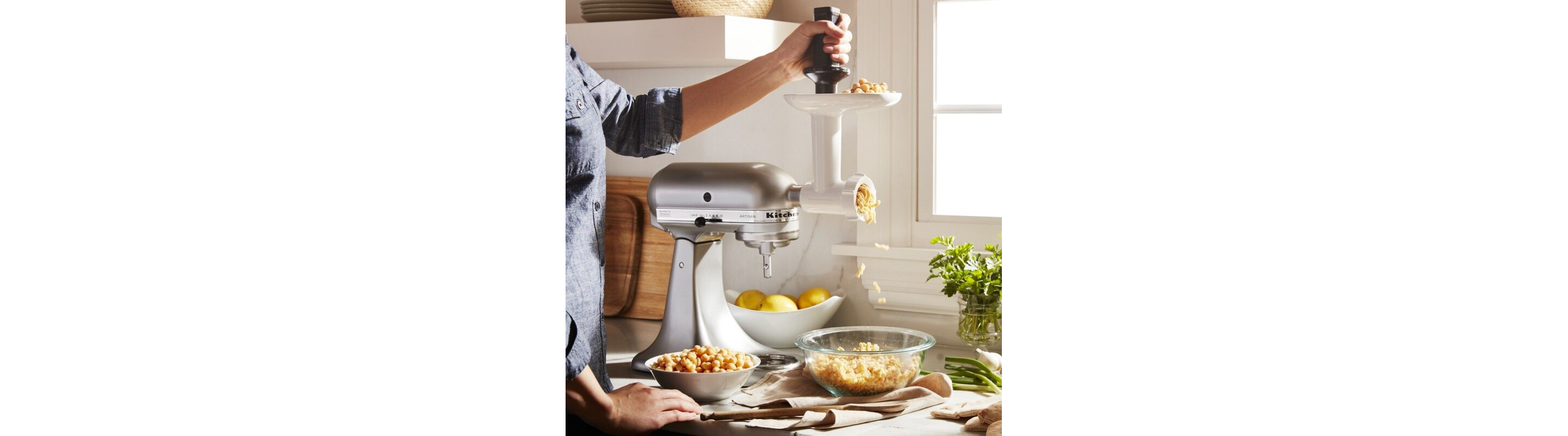 A person using a mini KitchenAid® stand mixer and shredding attachment.