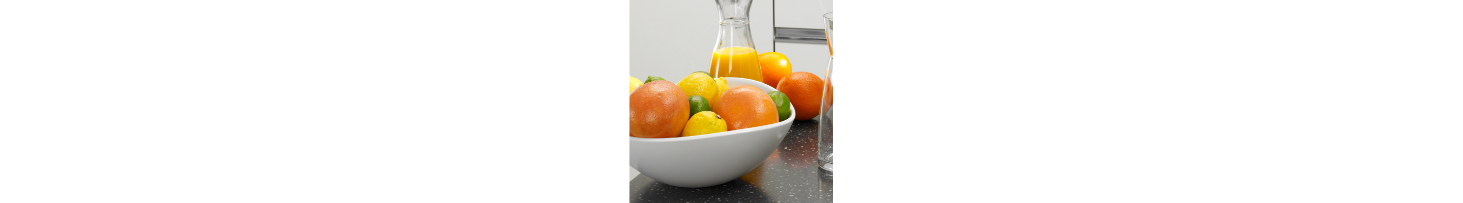 Freshly squeezed orange juice next to a bowl of fruit