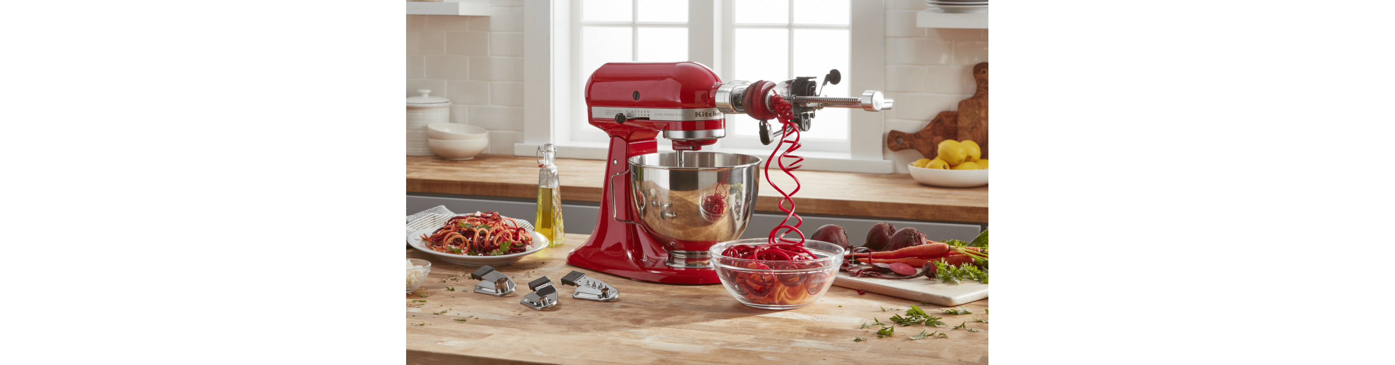 Spiralizer attachment spiralizing vegetables attached to red KitchenAid® stand mixer