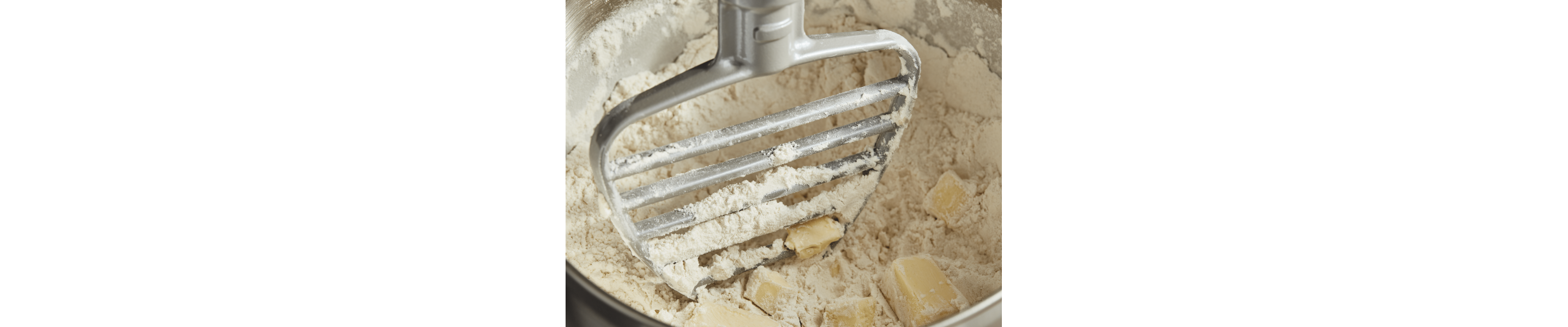 Paddle attachment cutting butter into flour in a mixing bowl 
