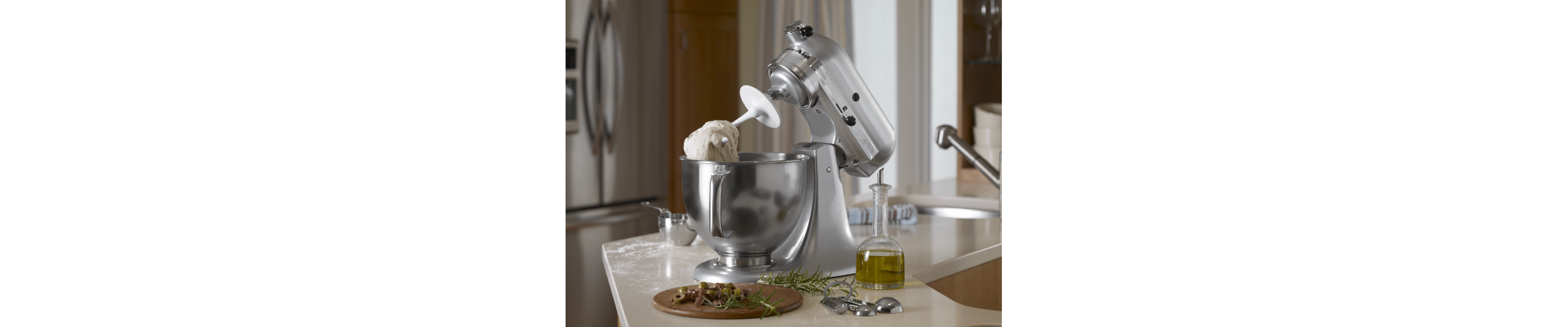 Tilt-head silver KitchenAid® Stand Mixer tilted upward with dough hanging on the dough hook above the mixing bowl 