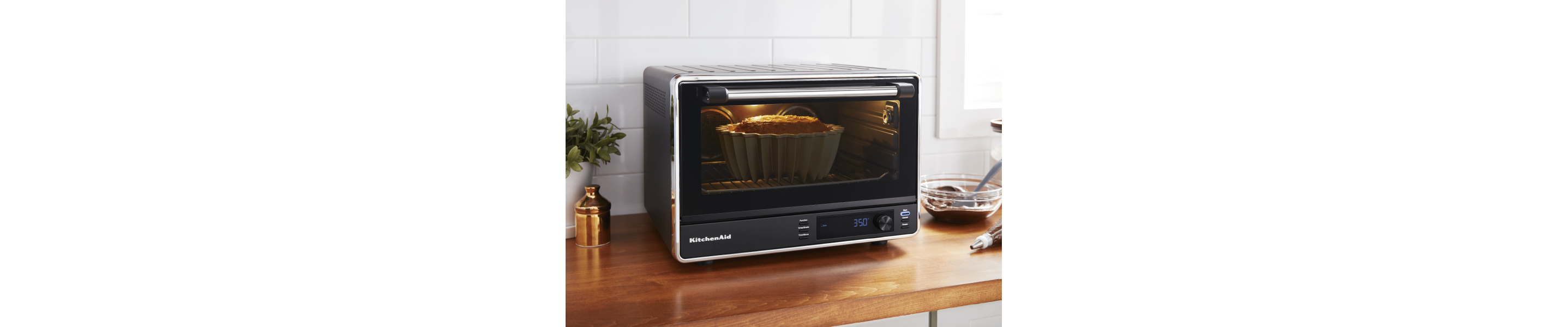 Black KitchenAid® countertop oven baking a bundt cake on brown countertop