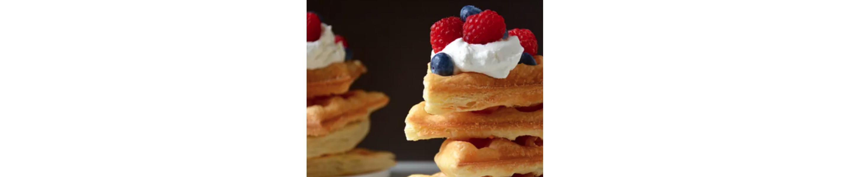 A mound of puff pastry waffles with whipped cream