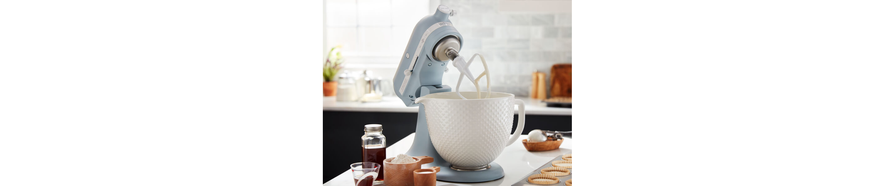 A KitchenAid® stand mixer with a flat beater accessory on the counter of a modern kitchen.