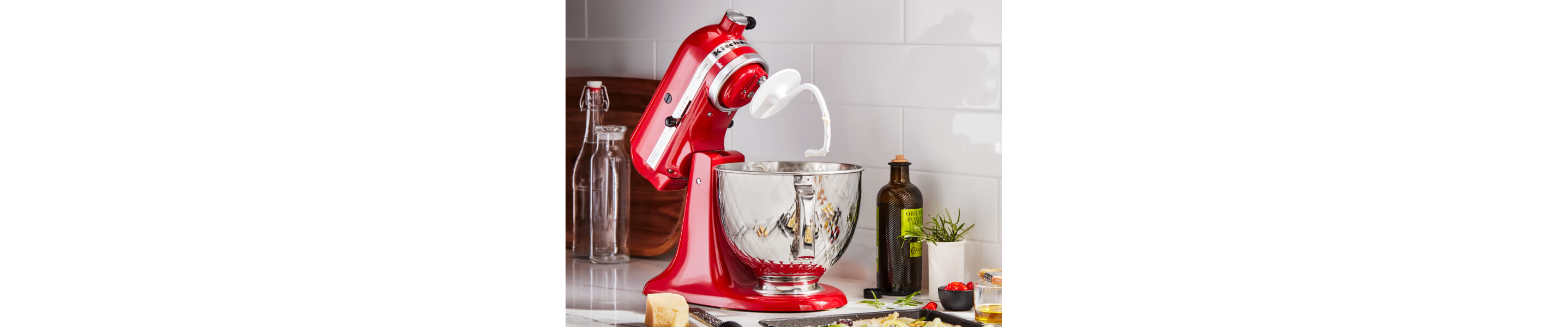 A KitchenAid® stand mixer with a dough hook accessory on the counter of a modern kitchen.
