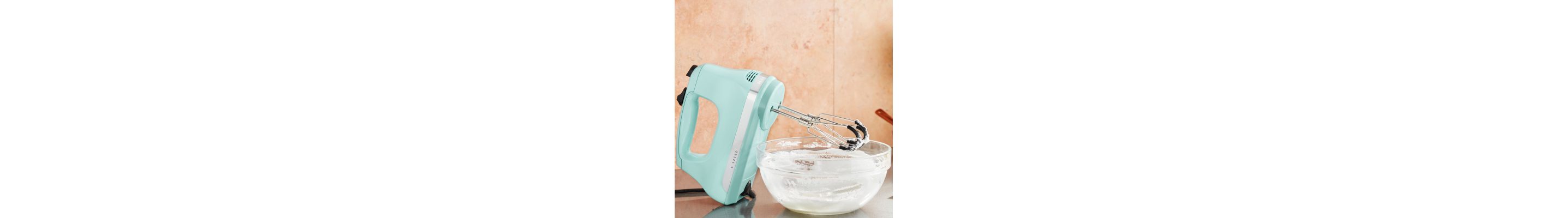 A corded hand mixer next to a bowl of icing
