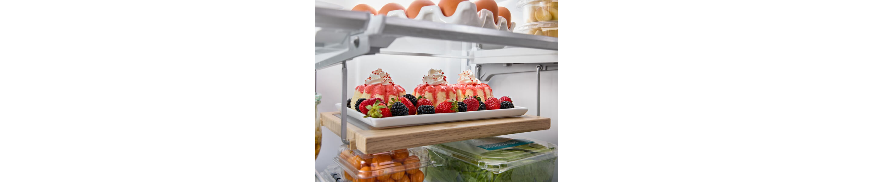 Three small bundt cakes with berries inside a KitchenAid® refrigerator
