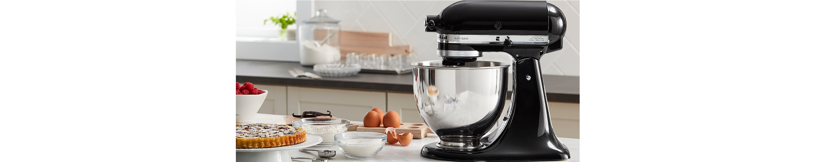 A hand blender with avocados and peppers on the counter.
